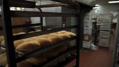 A baker pushing a baking rack through a kitchen Stock Footage 231414737