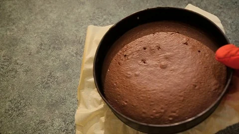 Baker put baked chocolate cake on kitchen table. Homemade chocolate cake. Fresh Stockbeeldmateriaal 81880016