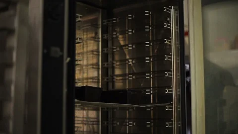 Baker puts a baking sheet with baking molds in the oven Video stock 106482497