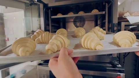 Baker puts baking sheet of raw croissants into the combi oven. Baking process Stock Footage 163144720