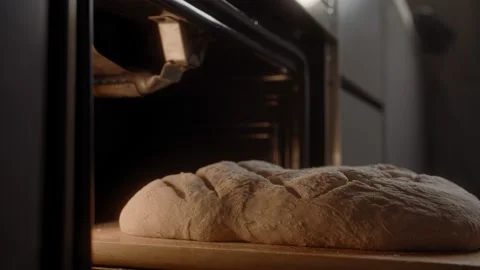 Baker puts beautiful homemade rustic bread with a pattern in the oven Stock Footage 168816777