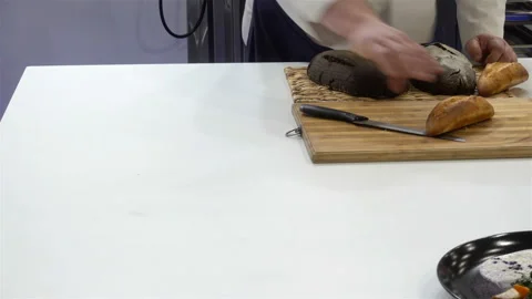 The baker puts bread on a cutting board in 4K Stock Footage 139859494