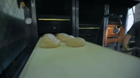 A baker puts bread into an industrial oven at a bakery 库存影片 89575808