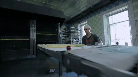A baker puts bread into an industrial oven at a bakery 스톡 동영상 89576509