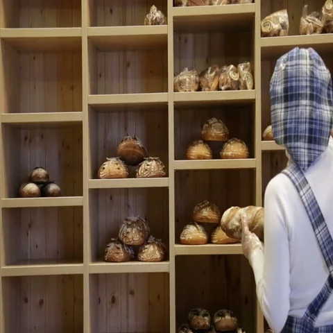 The baker puts bread on the shelves of his store Stock Footage 69484250