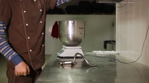 The Baker puts on elastic gloves near a large bowl Stockbeeldmateriaal 106482016