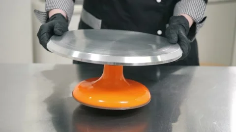 Baker puts elegant cake stand on grey table in kitchen Stock Footage 137932171