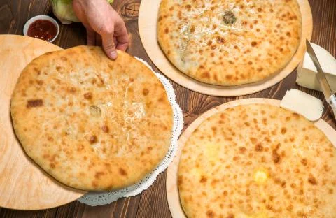 Baker puts Ossetian pie on the table Stock Photos