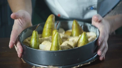 Baker puts pears cake dough lying in a baking dish. Pie and bakery products. Stock-Footage 124752234