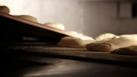 Baker puts raw bread into the bakery Stock Footage 74490878