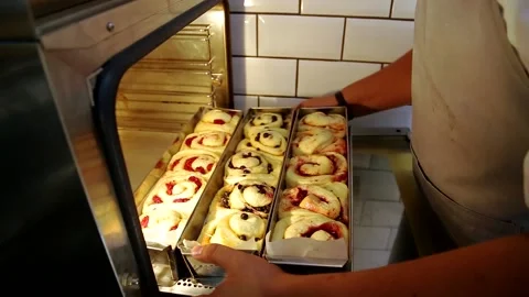 The baker puts raw buns in the oven to bake them	 Stock Footage 143402002