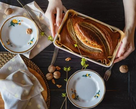 Baker puts on the table with utensils a pan with banana pie Stock Photos