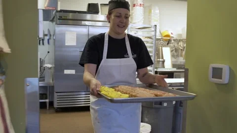 Baker putting cakes into a display case on a tray 動画素材 77094278