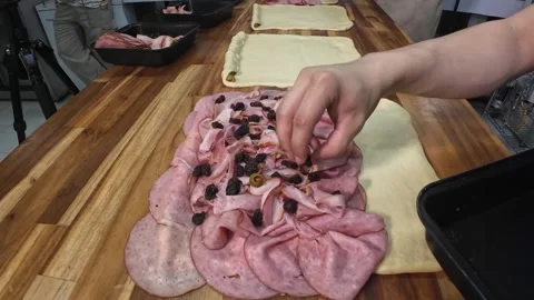 Baker putting raisins on raw ham bread dough in bakery Stock Footage 340196112