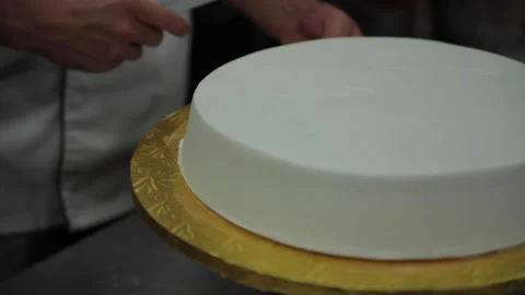 A baker removes icing from a cake with a spatula Stock Footage 231414542