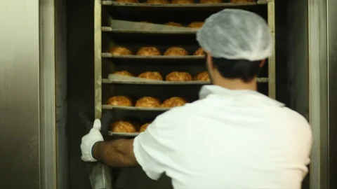 Baker removes a rack of bread from a oven Video stock 105080356