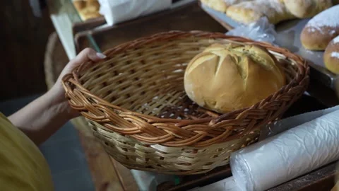 Baker removing fresh bread from basket Stockbeeldmateriaal 345375527