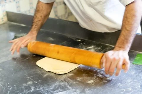 Baker Rolling Dough with Rolling Pin in Bakery Stock Photos