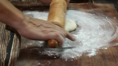 Baker rolling pizza dough on table before baking. Close up male hands rolls Stock Footage 150691917