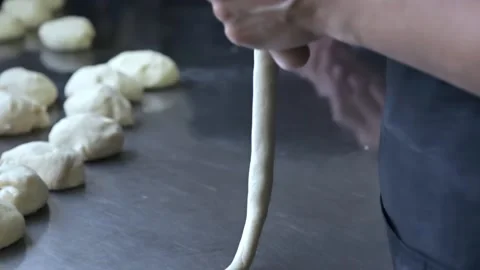Baker rolls the dough and wrap a sausage in Stock Footage 143585697