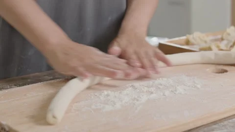 Baker Rolls Dough into Rope Shape on Wooden Board 動画素材 336530160