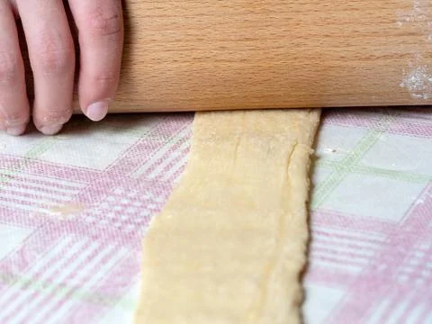 The Baker rolls the dough into strips on the kitchen table, sprinkled with fl Stock Photos