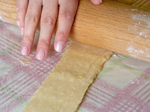 The Baker rolls the dough into strips with a rolling pin for cooking Stock Photos