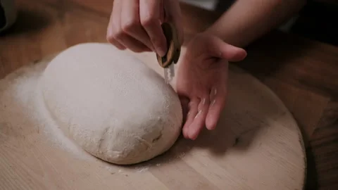 Baker scoring a loaf of bread with a razor blade Stock Footage 130386828