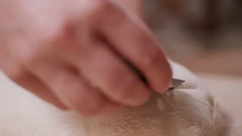 Baker scoring a loaf of dough before baking Stock Footage 130385972