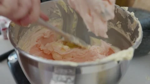 A baker scraps the inside of a mixer bowl with a spatula and gently taps the Stock Footage 319513387