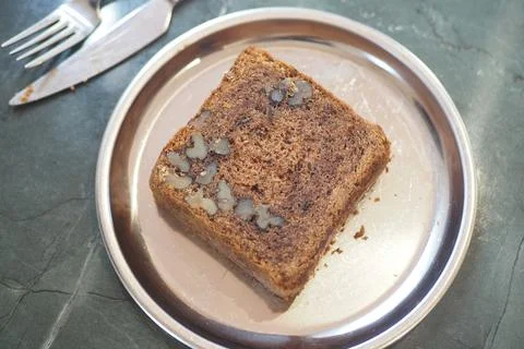 Baker serves a slice of walnut loaf cake on a silver plate Stock Photos