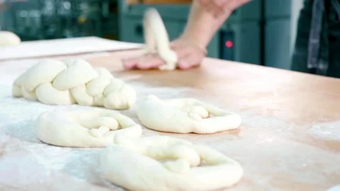 Baker shaping fresh dough to make pretzels and braided bread. Stock Footage 310609029