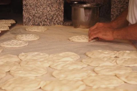 Baker shaping traditional bread on a work surface in a cozy kitchen 스톡 사진