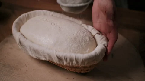 Baker sifting coating of flour onto dough in a basket Video stock 130385000