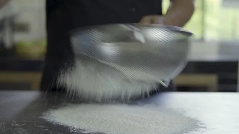 Baker sifting flour to prepare bakery products on a dark background Stock Footage 272501195