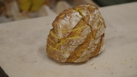 Baker slices crusty artisan bread on parchment paper ready for serving. Stock Footage 332105478