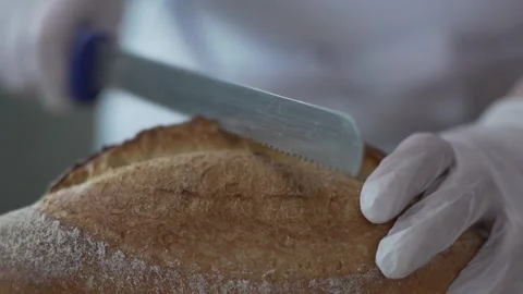 Baker slices hot bread taken from the oven extreme close up Stock-Footage 130356840