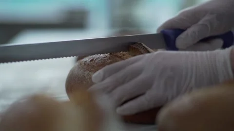 Baker slices hot bread taken from the oven close up Video stock 130356841