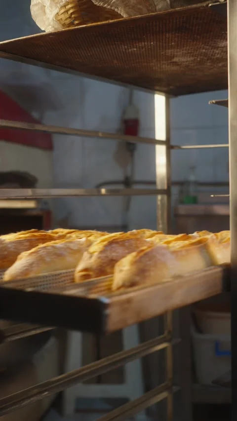 Baker Sliding a Tray of Freshly Baked Baguettes onto a Bakery Rack Stock Footage 345496162
