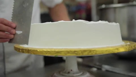 A baker smooths icing on a cake Stock Footage 231414564