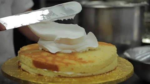 A baker smooths icing on a cake Stock Footage 231414585