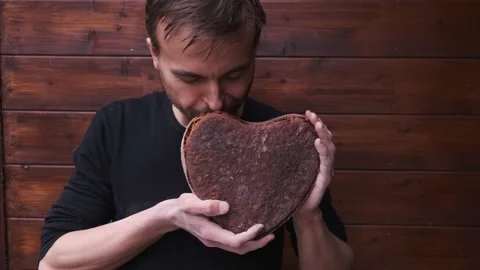 Baker sniffs handmade vegan rye sourdough bread in shape heart, valentine gift Video stock 130495312