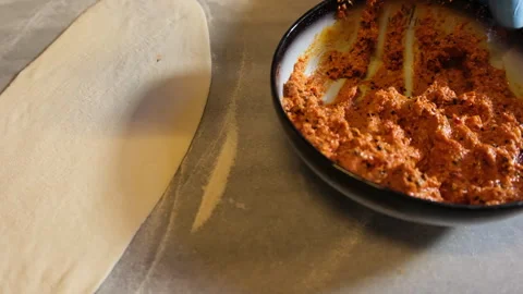 Baker spreading a minced meat mixture on a raw pide dough before baking Stock Footage 345408618