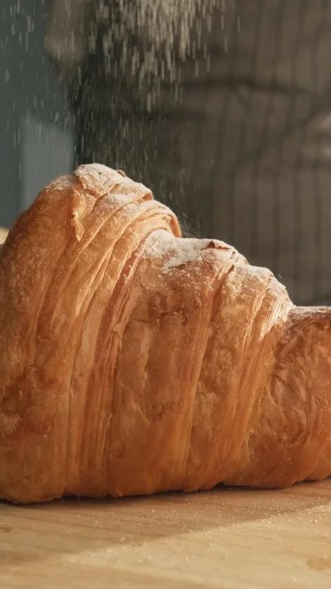 Baker sprinkle fresh croissant with powdered sugar on a wooden board. Vertical Stock Footage 309137148