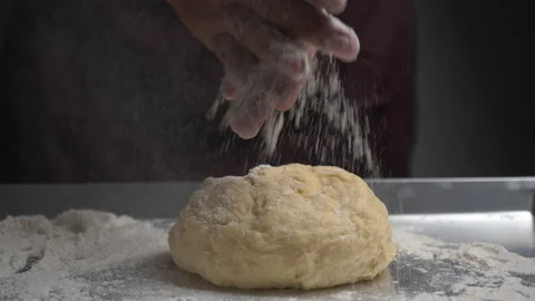 Baker sprinkling flour into dough on table Stock Footage 132679148
