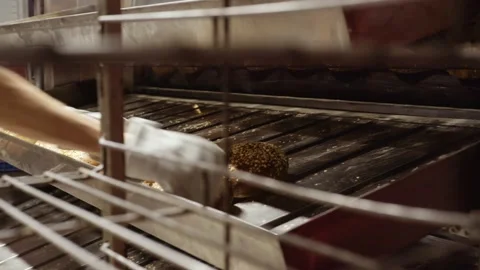 Baker standing in bakery sorting the fresh brown bread from the rack Stock Footage 143980457