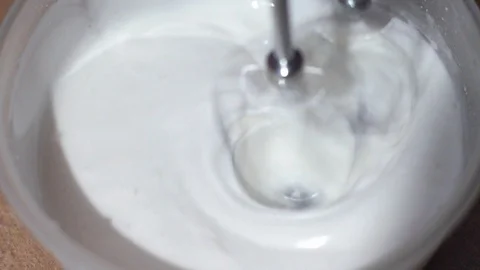 The baker stirs the egg whites with a mixer. Preparing dessert for Easter Stock Footage 128758707