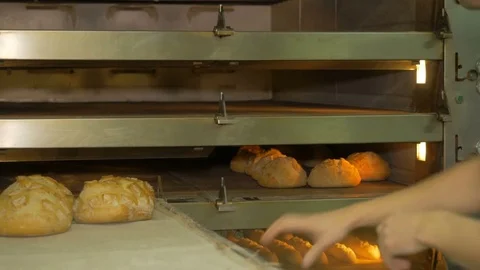 The baker takes bread out of the oven. Ready-made bakery products. Stock Footage 82712997