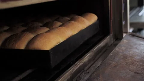 Baker takes the freshly baked bread out of the oven Stock Footage 130895259