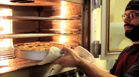 Baker taking cinnamon rolls out of the oven Stock Footage 8677553